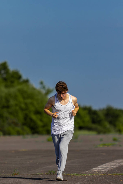 Young male caucasian adult jogging outside on a warm summer's day - 写真・画像