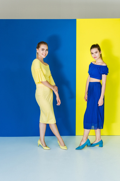 Modèles féminins en tenues bleues et jaunes posant sur des fonds assortis
 - Photo, image