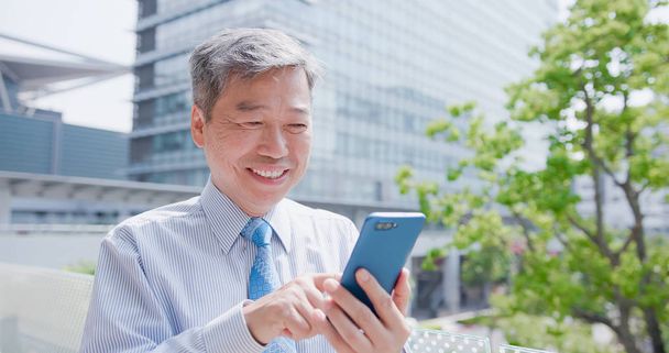 old businessman smiling  happily and using  phone - Foto, Bild