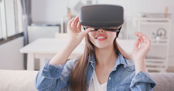 woman sitting  on sofa and wearing  virtual reality headset happily - Fotografie, Obrázek