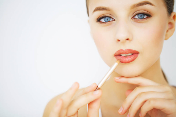 jonge vrouw die lippenstift aanbrengt - Foto, afbeelding
