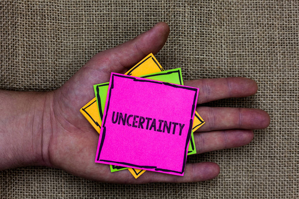 Text sign showing Uncertainty. Conceptual photo Unpredictability of certain situations events behavior Holding small pitches art papers thoughts ideas memories mat black shadow - Photo, Image