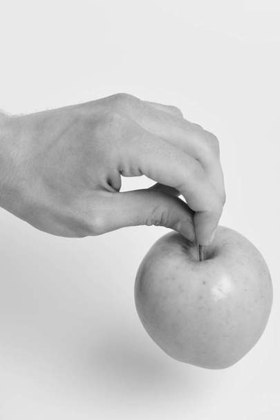 Male hand touches light green apple. Apple on white background - Φωτογραφία, εικόνα