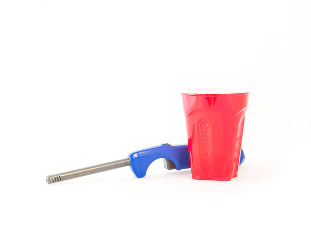 Studio Shot Party-Tasse und lange Küchenfeuerzeug isoliert auf weißem Hintergrund. roter Picknickbecher Recycling-Becher und Grill-Feuerzeug Nahaufnahme mit Clipping-Pfad und Kopierraum - Foto, Bild