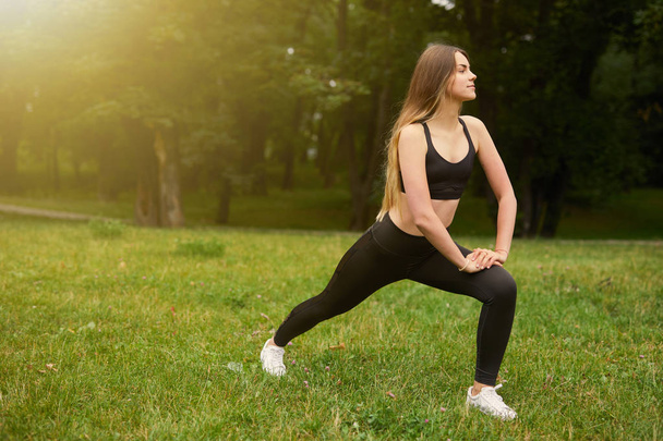 Sporty girl squats on the grass - Zdjęcie, obraz