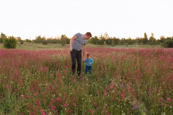 Taustakuva isästä ja pojasta kävelemässä pellolla auringonlaskun aikaan
 - Valokuva, kuva