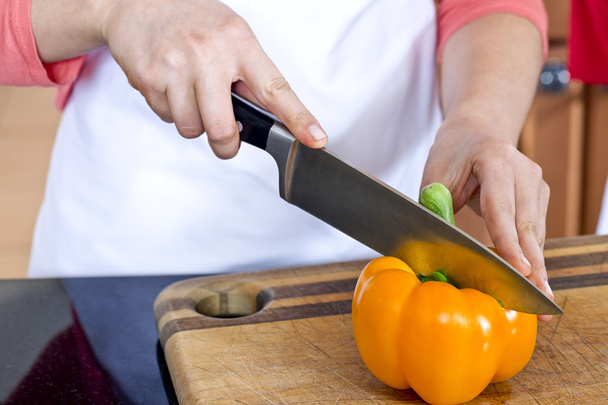 un couteau sur le point de trancher un poivron orange
 - Photo, image