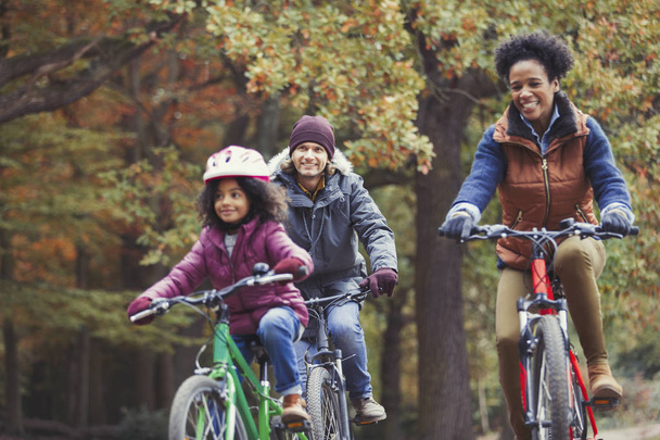 Jovem brincalhão pedalar em família no parque de outono
 - Foto, Imagem