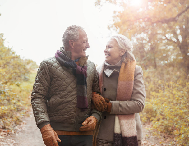 Liebevolles Senioren-Paar geht Arm in Arm auf Pfad im Herbstpark - Foto, Bild