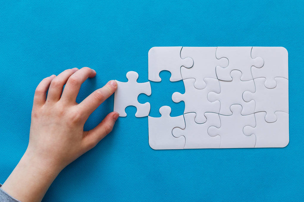 Last piece jigsaw in hand. Concept success of business. Blue background - 写真・画像
