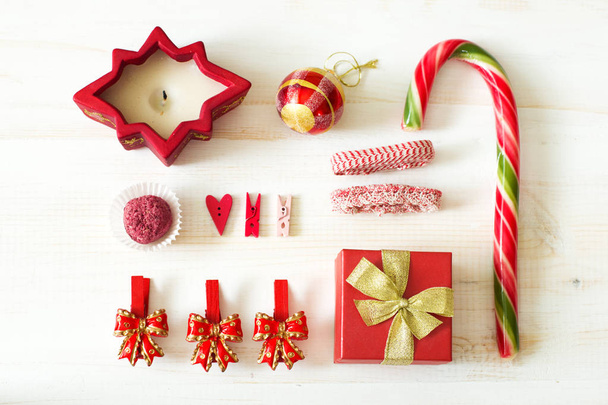 Karácsonyi díszek (gyertya, édességek, csapok, ajándék és szalagok) fehér fa háttér halmaza. Lapos feküdt - Fotó, kép
