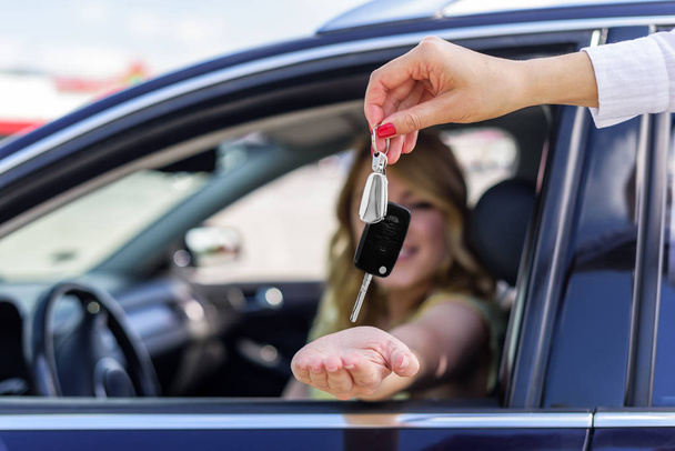Привлекательная женщина в машине получает ключи от машины. Аренда или покупка авто
. - Фото, изображение