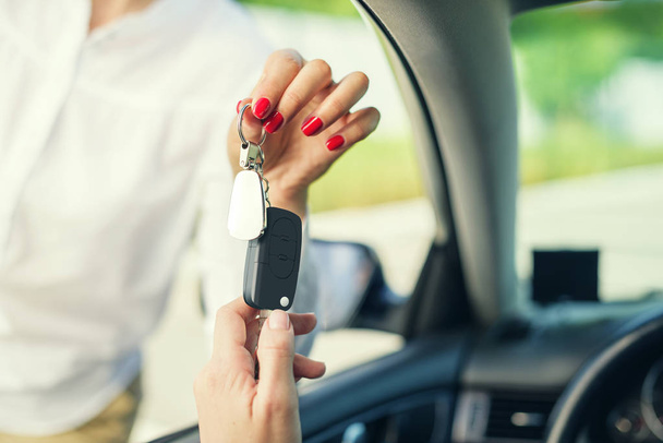 Μια ελκυστική γυναίκα σε ένα αυτοκίνητο παίρνει τα κλειδιά του αυτοκινήτου. Ενοικίαση ή αγορά του auto. - Φωτογραφία, εικόνα