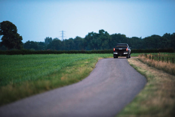 Camioneta que conduce en la carretera del campo por la noche
 - Foto, imagen
