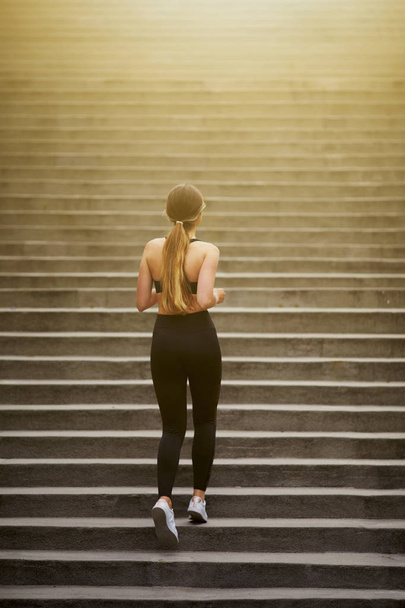 Fit pretty girl running up stairs with city background - Fotoğraf, Görsel