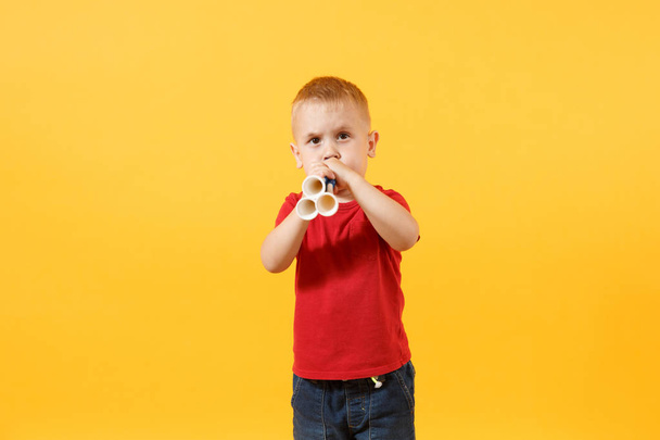 Malé roztomilé dítě chlapeček 3-4 let, fotbalový fanoušek v červené tričko, držící v ruce trubku, foukání izolované na žlutém pozadí. Děti životní styl rodinné rekreační sport koncept. Kopírovat reklamní prostor - Fotografie, Obrázek