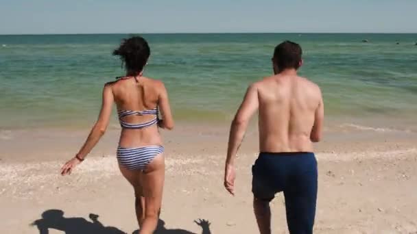 A couple in swimsuits come rapidly into the sea water - Filmmaterial, Video