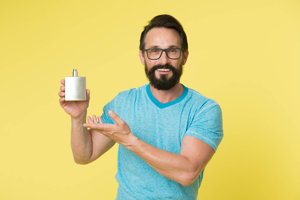 Right perfume fragrance makes you younger. Man bearded handsome smiling face hold bottle perfume defocused. How to pick right fragrance. How to choose best perfume for men according to occasion - Photo, image