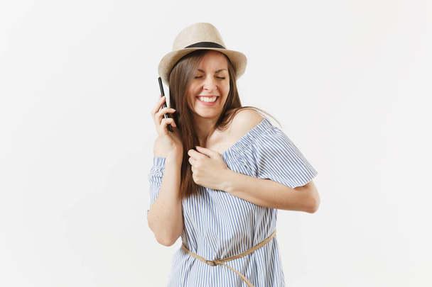 Lachende vrouw gekleed blauwe jurk, hoed praten op mobiele telefoon, uitvoeren van aangenaam gesprek geïsoleerd op een witte achtergrond. Mensen, oprechte emoties, lifestyle concept. Gebied van de reclame. Kopiëren van ruimte - Foto, afbeelding