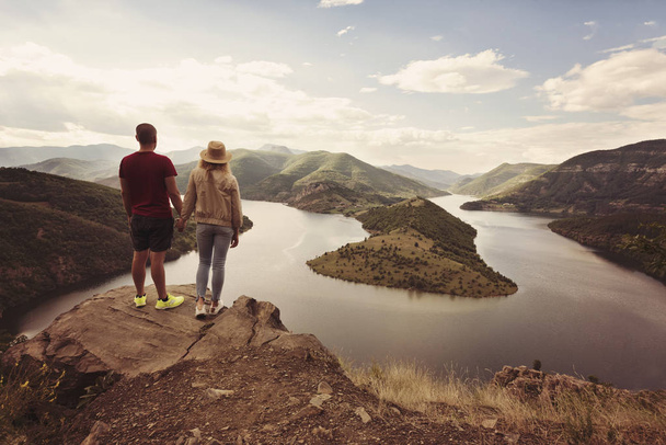 Hiking couple looking at the view holding hands. Location: the meanders of Arda river, Bulgaria. - Φωτογραφία, εικόνα