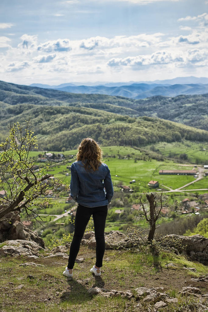 A hiking girl sits on the edge of the cliff and looking at the  valley and mountains. - Φωτογραφία, εικόνα