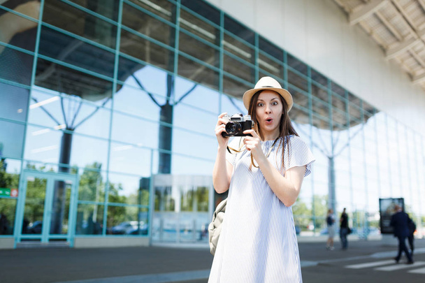 Młody podróżnik szoku turystycznych Kobieta w kapeluszu plecak trzymać retro vintage zdjęcie aparatu w międzynarodowym porcie lotniczym. Kobiece pasażera podróżowania za granicą, podróż na weekendy wypad. Koncepcja lot Air - Zdjęcie, obraz