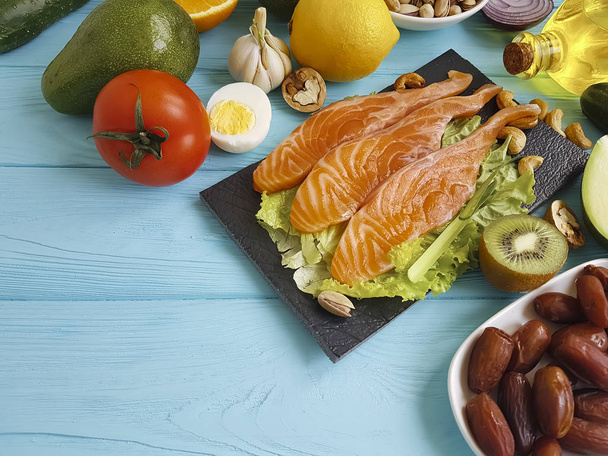 vis, tomaten, avocado en noten op een houten achtergrond - Foto, afbeelding