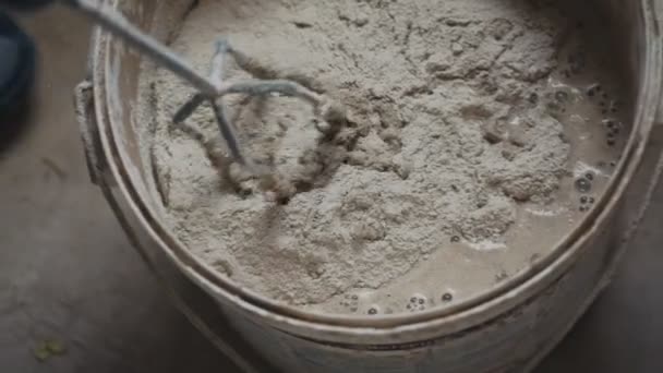 Electric mixer mixes cement in a bucket at a construction site - Кадри, відео