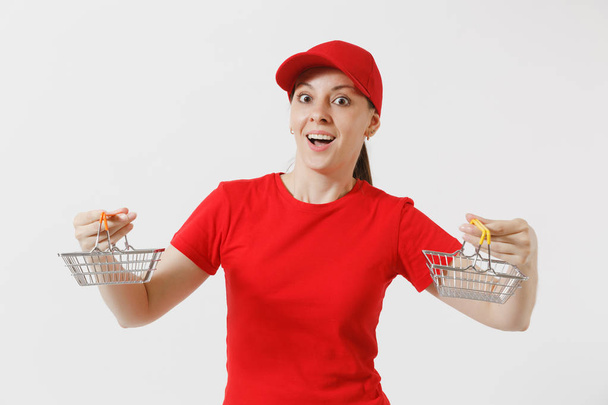 Dodávky žena v červených uniformách izolovaných na bílém pozadí. Ženské courier nebo prodejce v čepici, triko, džíny drží kovové s potravinami košík na nákupy v supermarketu. Kopírovat prostor pro reklamu - Fotografie, Obrázek