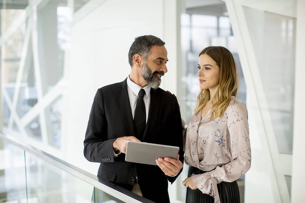Young businesswoman and businessman look on digital tablet and discuss about new project in modern office - Fotoğraf, Görsel