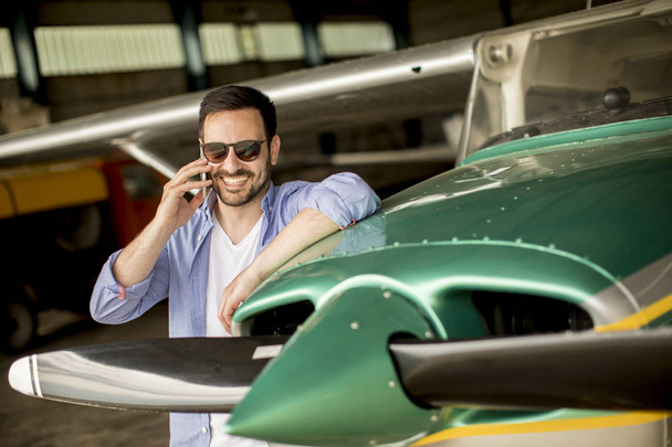 Handsome young pilot checking airplane  in the hangar - Photo, Image