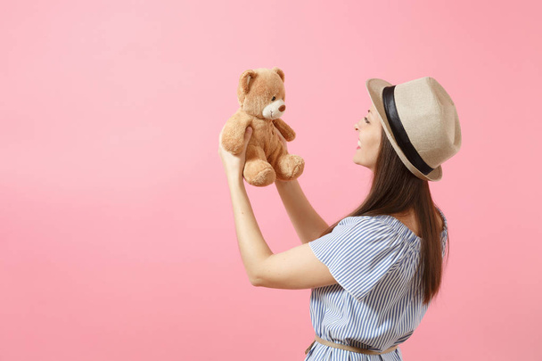 Porträt einer jungen schönen Frau in blauem Kleid, Sommer-Strohhut mit Teddybär-Plüschtier isoliert auf rosa Hintergrund. Menschen, aufrichtige Emotionen, Lebensstil-Konzept. Werbefläche. Kopierraum - Foto, Bild
