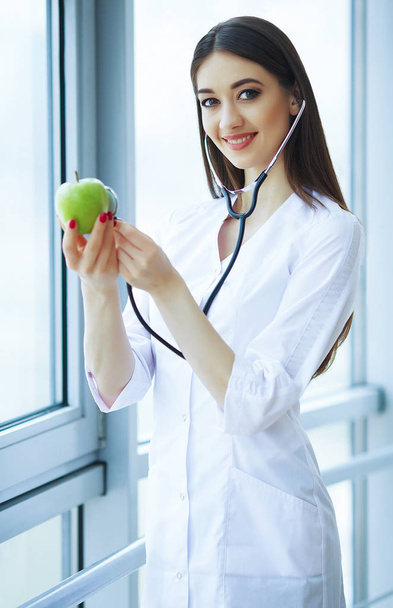Gezondheid en schoonheid. De diëtist houdt verse groenten en fruit in de handen. Jonge arts met een mooie glimlach. Hoge resolutie - Foto, afbeelding