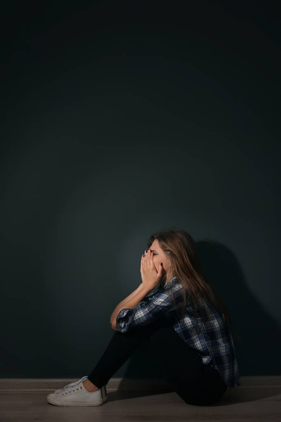 Depressed young woman sitting on floor in darkness - Фото, зображення