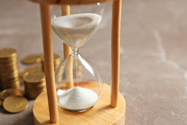 Hourglass with flowing sand and coins on table. Time management - Foto, immagini