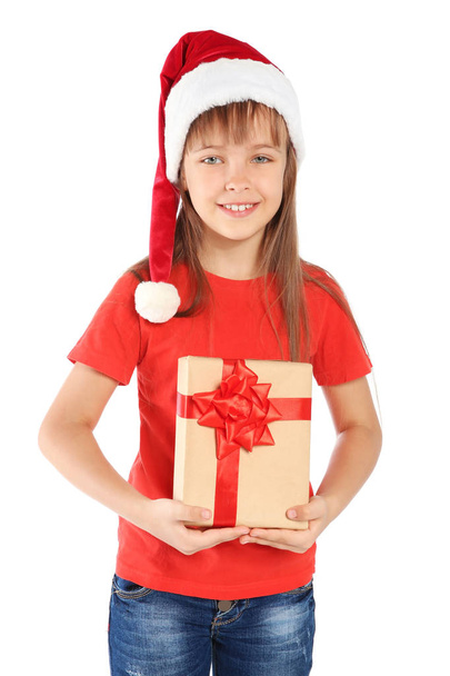 Cute little child in Santa hat with Christmas gift on white background - Фото, изображение