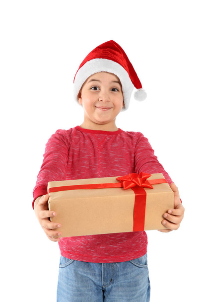 Cute little child in Santa hat with Christmas gift on white background - Foto, imagen