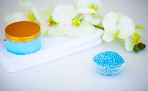 Sal Orgânico do Mar Azul. Composição de spa com creme, sal, toalha e flores em um fundo branco. Produtos e cosméticos de bem-estar
. - Foto, Imagem