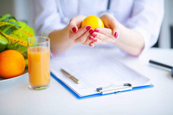 Diet. Doctor Nutritionist hold lemon in her office. Concept of natural food and healthy lifestyle. Fitness and healthy food diet concept. Balanced diet with vegetables. - Фото, зображення