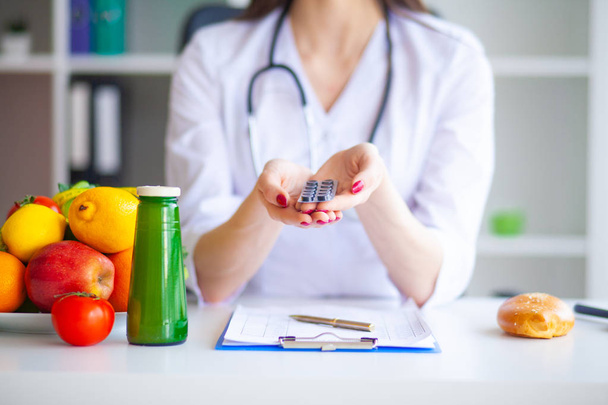Diet. Doctor Nutritionist hold pills in her office. Concept of natural food and healthy lifestyle. Fitness and healthy food diet concept. Balanced diet with vegetables. - 写真・画像