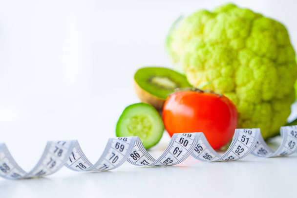 Dieta. Fitness y alimentación saludable concepto de dieta. Dieta equilibrada con verduras. Verduras verdes frescas, cinta métrica sobre fondo blanco. Primer plano.
 - Foto, imagen