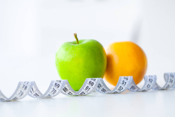 Diet. Fitness and healthy food diet concept. Balanced diet with fruit. Fresh green fruit, measuring tape on white background. Closeup - Photo, Image