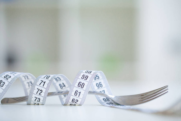 ダイエットや体重コントロールの概念。センチのテープとテキストを挿入する場所で白い背景にフォーク。健康, 減量, ダイエット, 栄養の概念。フィットネスと健康食品ダイエット コンセプト. - 写真・画像