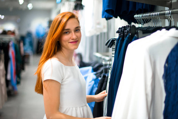 Young redhead pretty girl buying at a clothing store - Zdjęcie, obraz