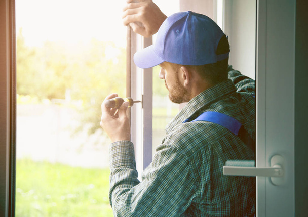 service man installing window with screwdriver - Foto, Imagen