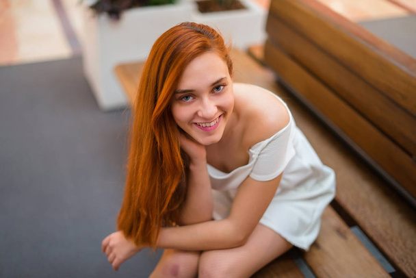 Young redhead pretty girl sitting on a bench - 写真・画像