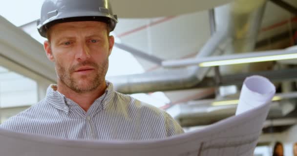 Male architect looking at blueprint in office 4k - Felvétel, videó