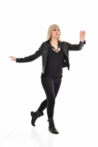 Portret van de volledige lengte van blond meisje dragen zwart lederen kleding, staande pose. geïsoleerd op witte studio achtergrond. - Foto, afbeelding