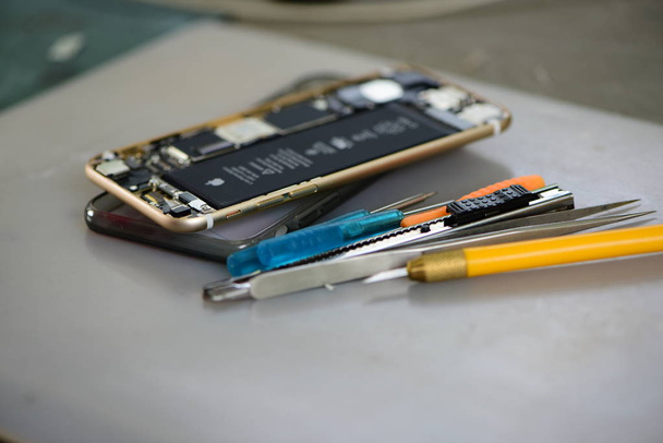 Aufgebrochenes Handy mit Werkzeug aus nächster Nähe - Foto, Bild