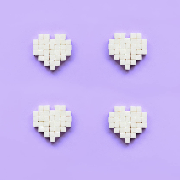 A few hearts made of sugar cubes lies on a trendy pastel violet background. - Photo, image